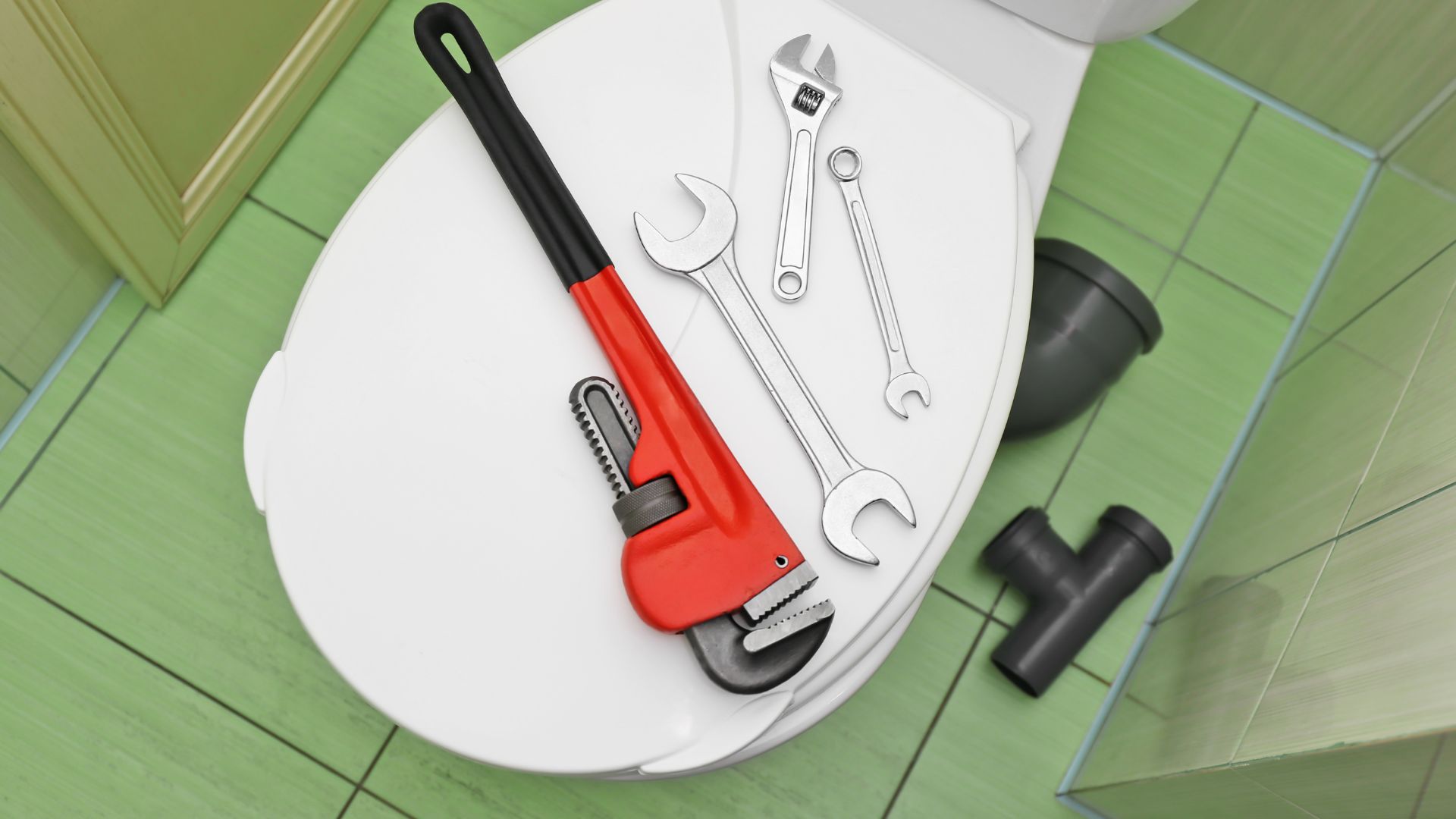 A toilet with a wrench, wrench and other tools on it